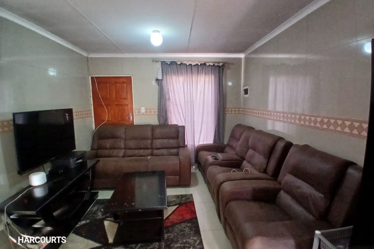 A living room featuring tiled walls, a coved ceiling, and a timber door, providing a functional space for relaxation.