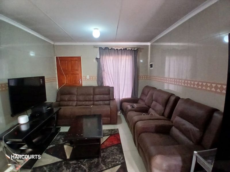 A living room featuring tiled walls, a coved ceiling, and a timber door, providing a functional space for relaxation.