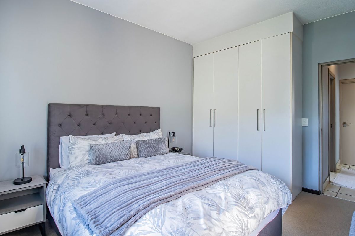 A well-maintained bedroom featuring neutral wall tones, carpeted flooring, and ample built-in cupboard storage space.