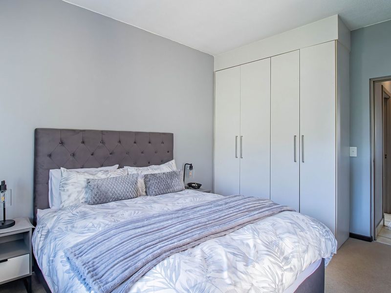 A well-maintained bedroom featuring neutral wall tones, carpeted flooring, and ample built-in cupboard storage space.