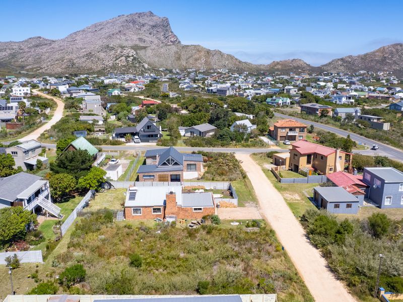 Aerial view of a residential neighborhood set against a scenic mountain backdrop, featuring established homes and local access roads.