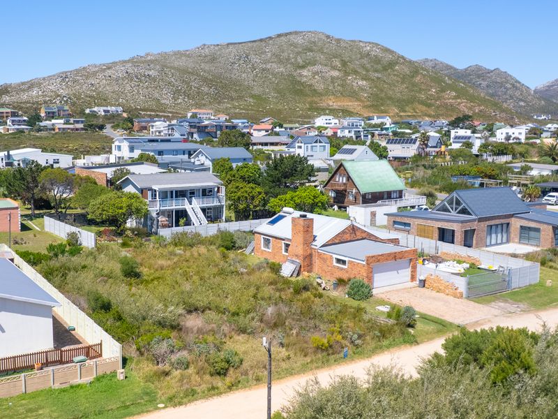 An aerial view of a vacant residential plot situated within an established neighborhood, featuring mountain views and surrounding residential properties.