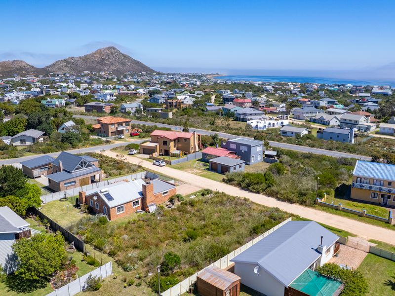 Aerial view of a residential coastal neighborhood featuring surrounding homes, natural landscape, and proximity to the ocean.