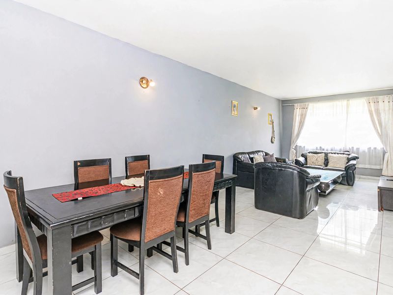 Spacious open-plan living and dining area featuring neutral wall tones and polished tiled flooring, offering a versatile layout for modern apartment living.