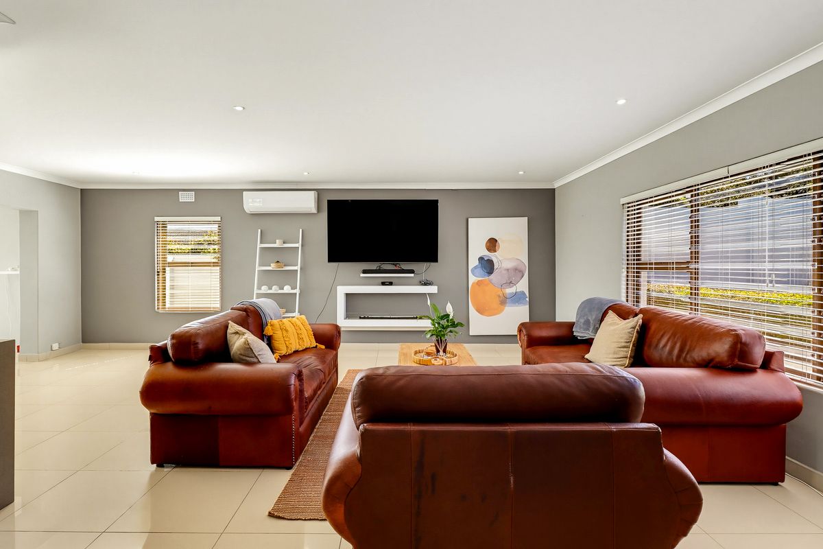Spacious living room featuring neutral grey walls, tiled flooring, recessed downlighting, and a wall-mounted split-system air conditioner.