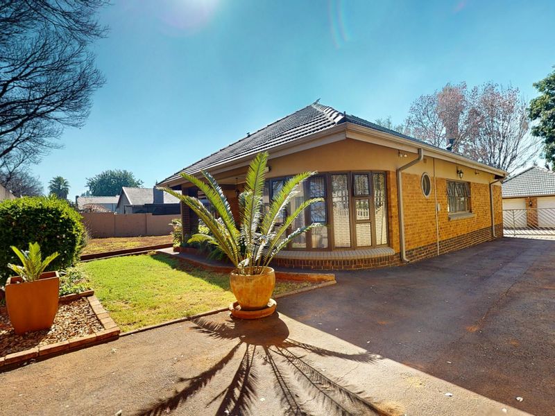 Front view of a single-story brick house featuring a bay window, tiled roof, and a paved driveway leading to the property entrance.