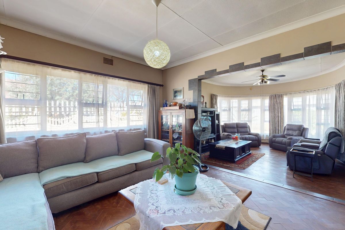 Spacious living area featuring classic parquet flooring, a decorative archway, and large windows that provide ample natural light.