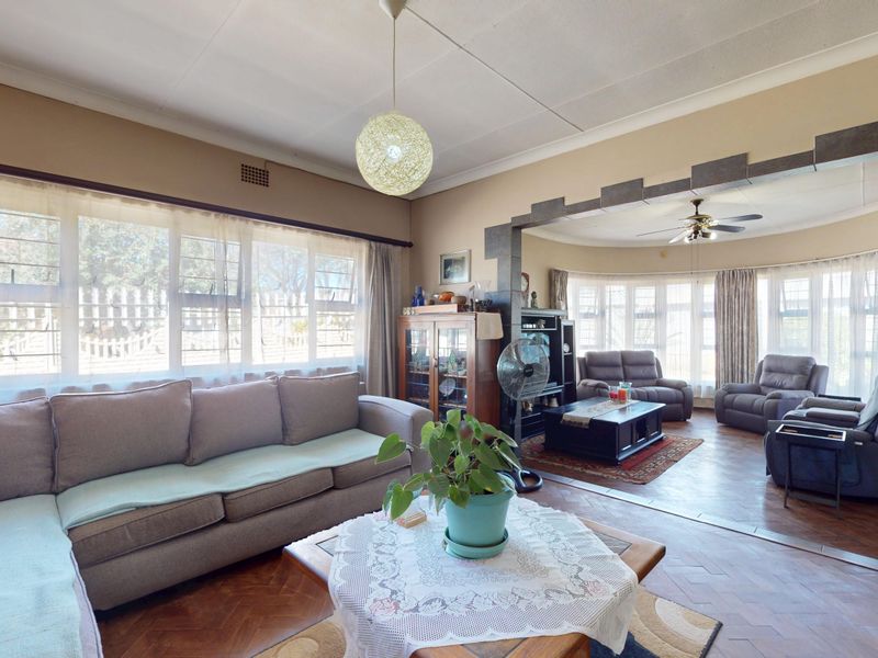 Spacious living area featuring classic parquet flooring, a decorative archway, and large windows that provide ample natural light.