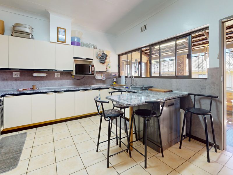 Functional kitchen featuring ample built-in cabinetry, granite countertops, a gas stove, and direct access to an outdoor patio area.