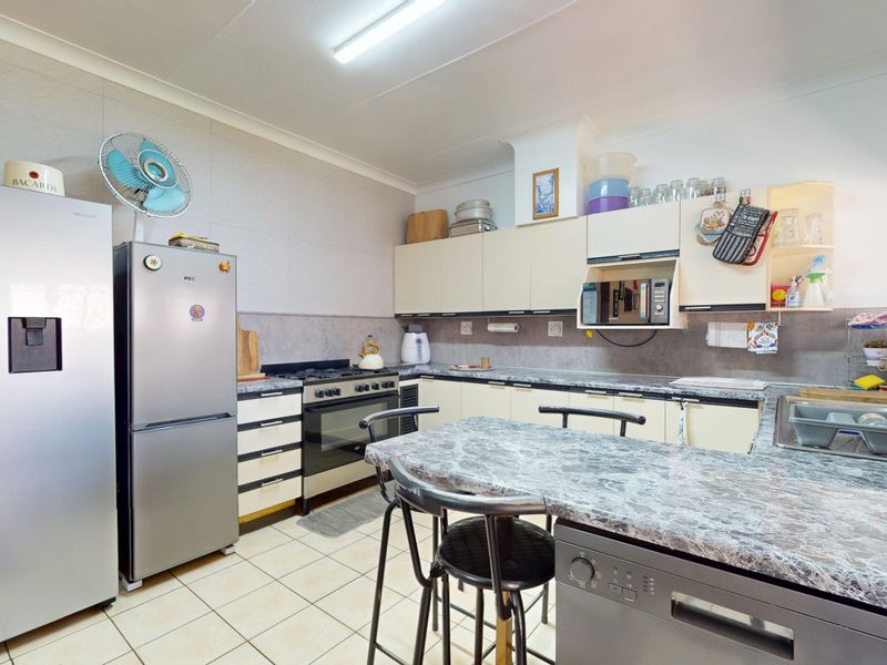A functional kitchen featuring built-in cabinetry, laminate countertops, a gas stove, and tiled flooring, offering a practical layout for daily meal preparation.