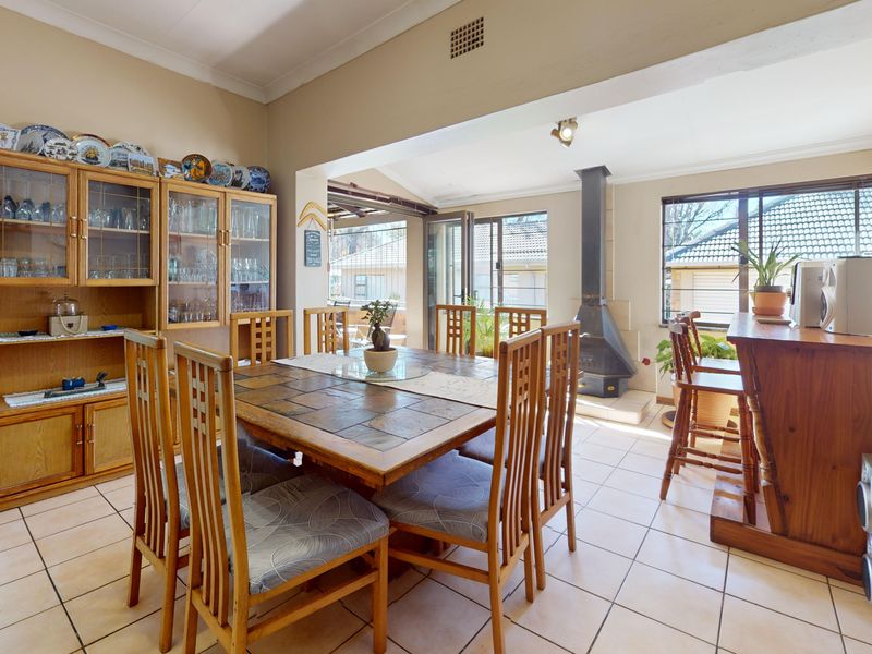 Open-plan dining area featuring tiled flooring, a freestanding fireplace, and a built-in breakfast bar, with direct access to the outdoor patio area.