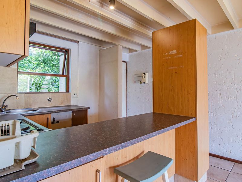 A functional kitchen featuring laminate cabinetry, a breakfast bar, and exposed ceiling beams, offering a dated aesthetic ready for modern updates.