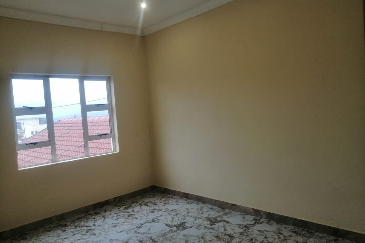 An empty bedroom featuring tiled flooring, neutral walls, and a window with natural light.