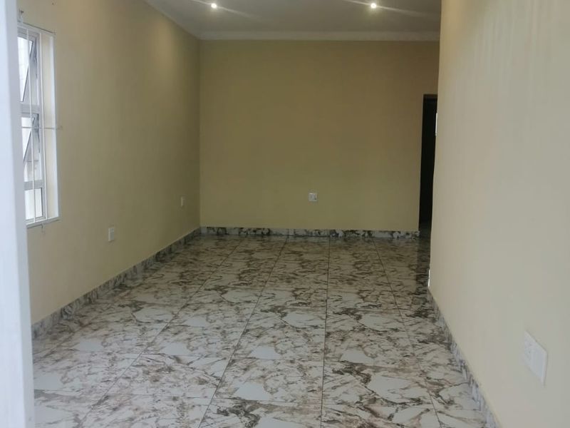 An empty, well-lit living area featuring modern marble-patterned floor tiles and a combination of recessed downlights and a decorative central light fixture.