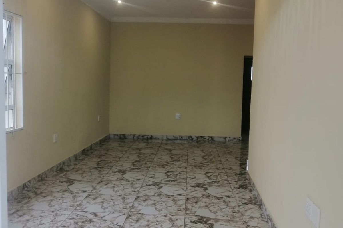 A bright, empty living area featuring modern marble-patterned floor tiles, recessed downlighting, and a decorative central light fixture.