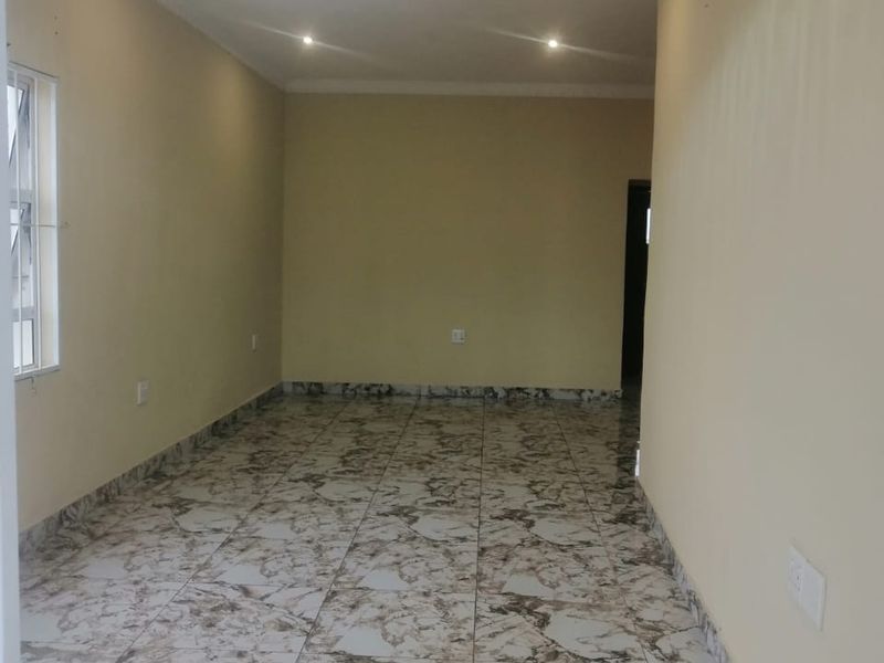 A bright, empty living area featuring modern marble-patterned floor tiles, recessed downlighting, and a decorative central light fixture.