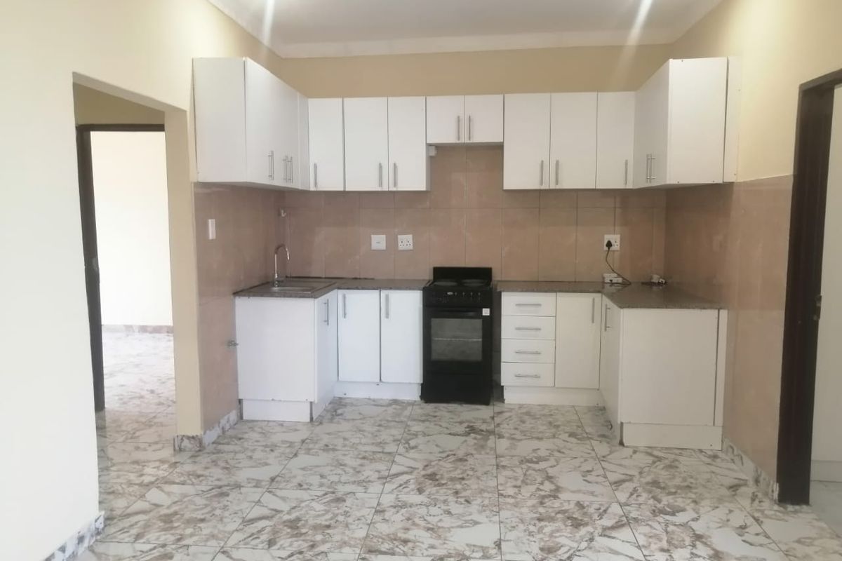 A clean, functional kitchen featuring white cabinetry, granite countertops, tiled backsplash, and a freestanding stove, offering a bright and practical cooking space.