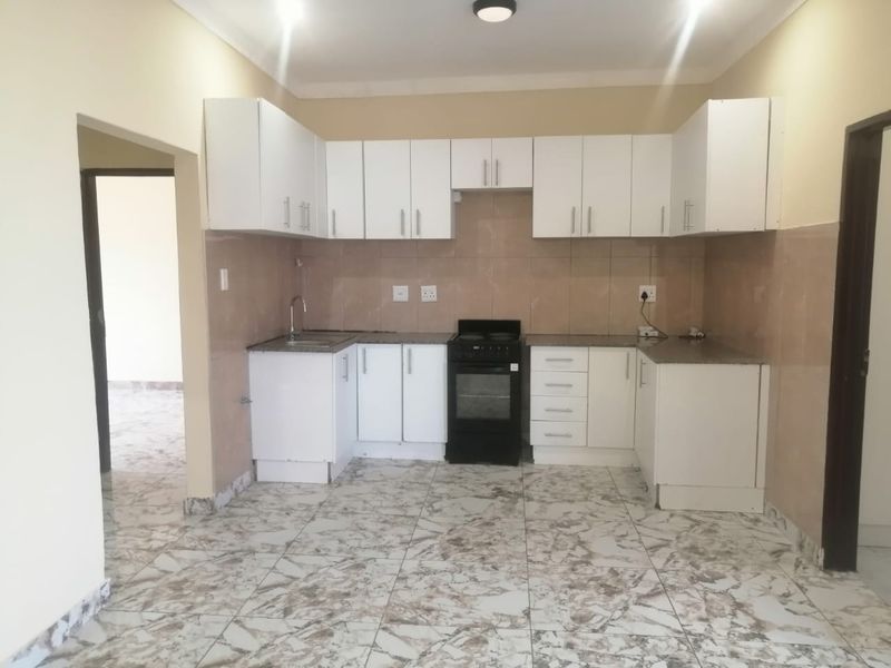 A clean, functional kitchen featuring white cabinetry, granite countertops, tiled backsplash, and a freestanding stove, offering a bright and practical cooking space.