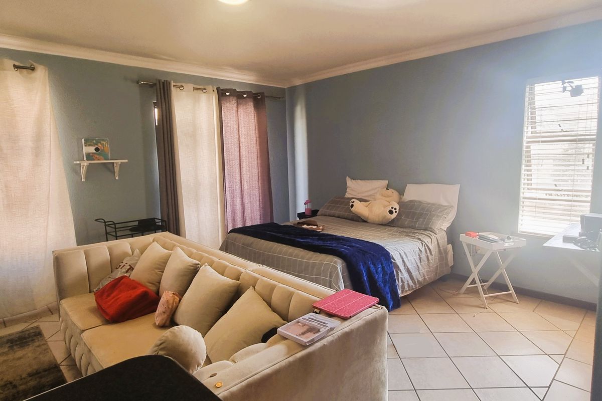 Spacious bedroom featuring tiled flooring, neutral wall tones, and natural light through large windows.