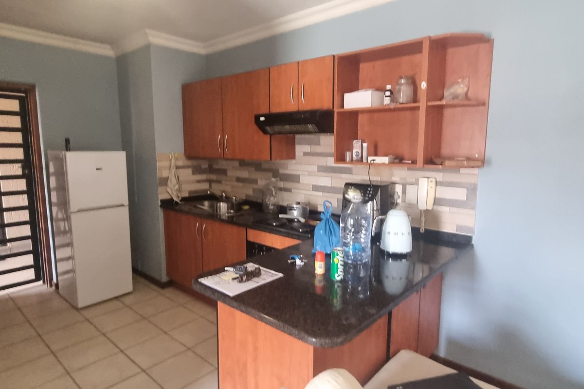 A functional kitchen featuring wooden cabinetry, stone countertops, a tiled backsplash, and a breakfast bar, providing a practical layout for daily meal preparation.