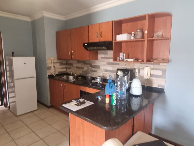 A functional kitchen featuring wooden cabinetry, stone countertops, a tiled backsplash, and a breakfast bar, providing a practical layout for daily meal preparation.
