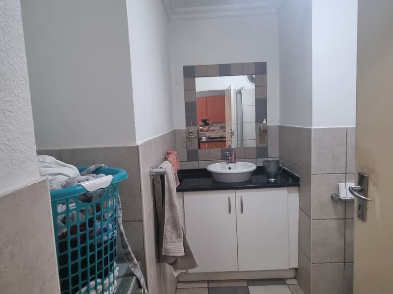 A functional bathroom featuring a vanity cabinet with a vessel sink, tiled walls, and a framed mirror.