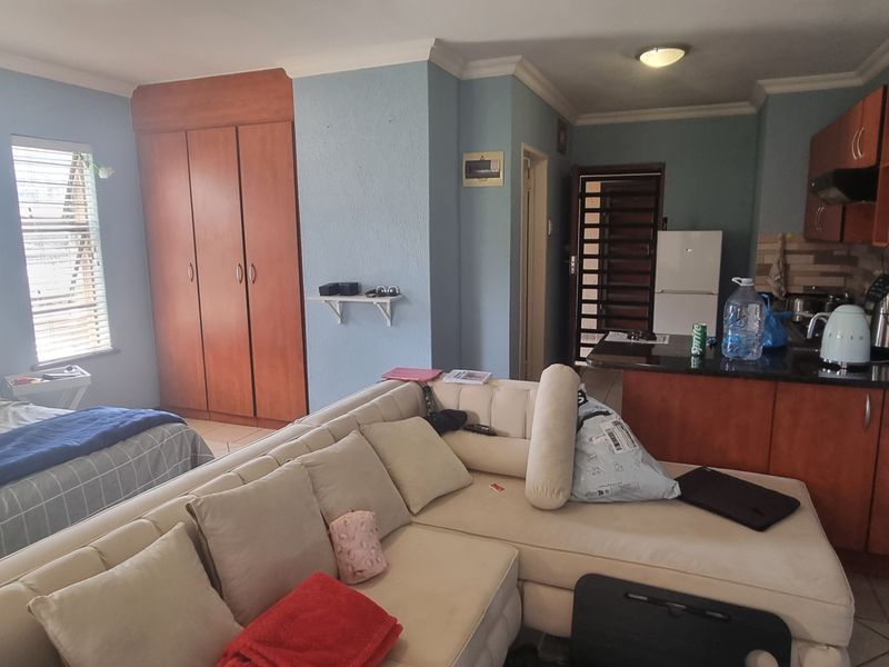 Open-plan studio apartment featuring a compact kitchen with built-in cabinetry, granite countertops, and tiled flooring throughout.