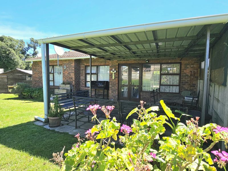 A covered outdoor patio area featuring brick construction and paved flooring, overlooking a private garden space.