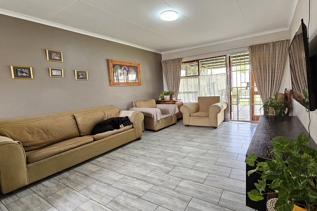 A well-maintained living room featuring neutral tiled flooring and a sliding glass door providing access to the outdoor area.
