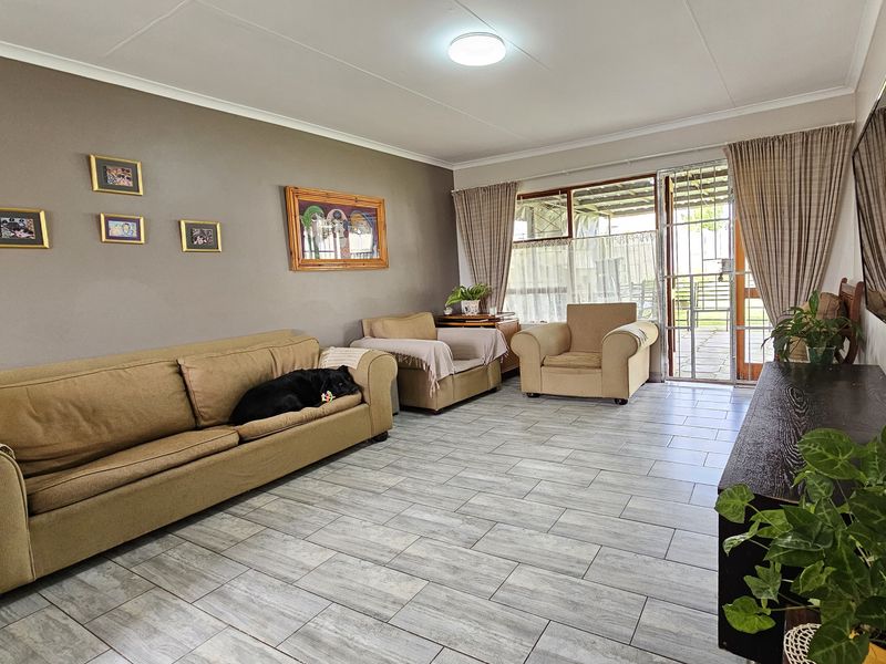 A well-maintained living room featuring neutral tiled flooring and a sliding glass door providing access to the outdoor area.