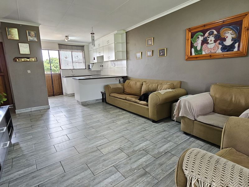 Open plan living area featuring tiled flooring and a functional kitchen with built-in cabinetry and countertop, providing a versatile space for daily living.