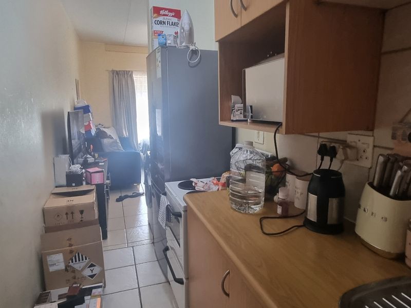 An open-plan kitchen and living area featuring tiled flooring, built-in cabinetry, and a freestanding stove, requiring cosmetic updates to improve the space.