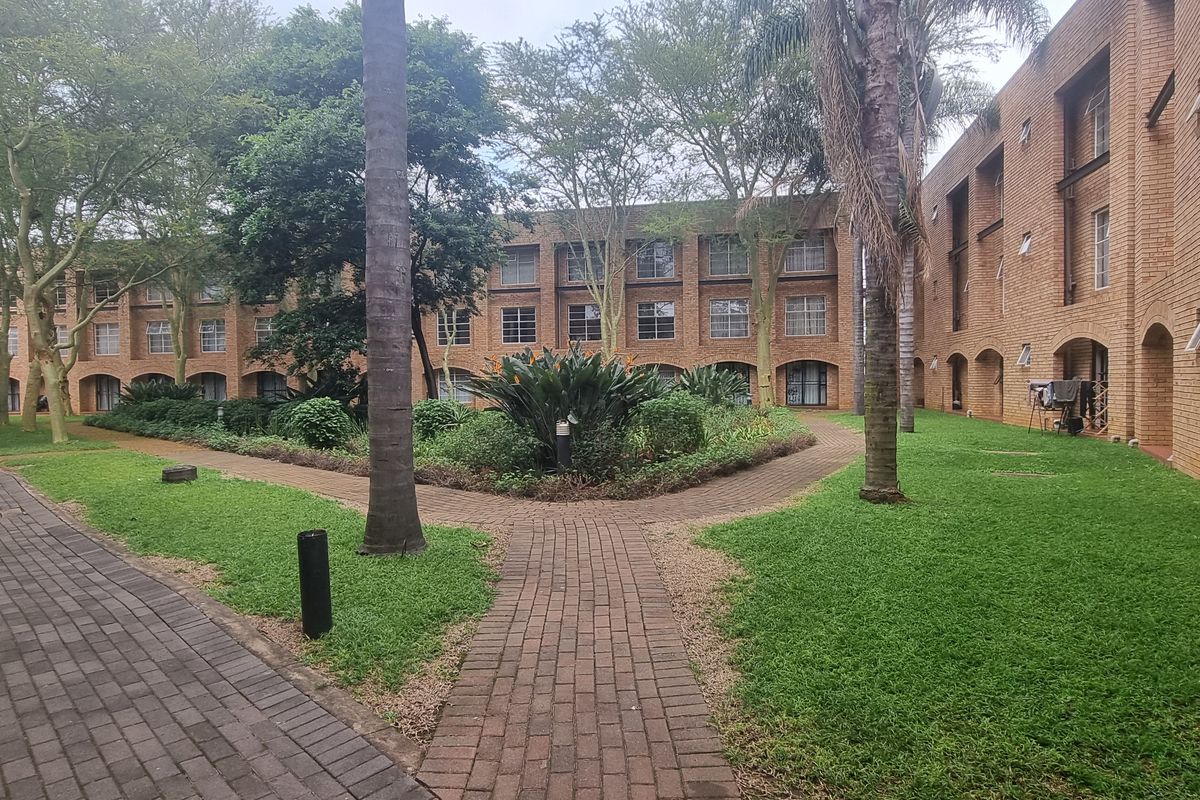 A view of the apartment complex courtyard featuring brick building facades, manicured lawns, and paved walkways between the residential blocks.