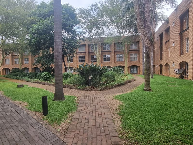 A view of the apartment complex courtyard featuring brick building facades, manicured lawns, and paved walkways between the residential blocks.