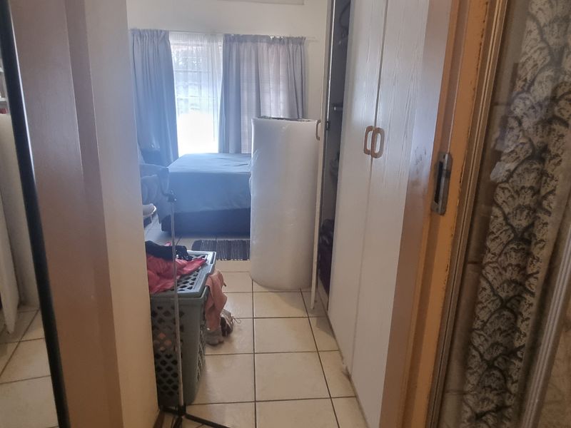 A narrow hallway featuring built-in storage cupboards and tiled flooring, providing access to adjacent living areas.