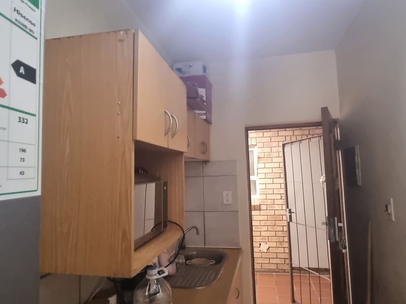 A functional scullery area featuring built-in cabinetry, a stainless steel sink, and a security gate leading to an exterior space.