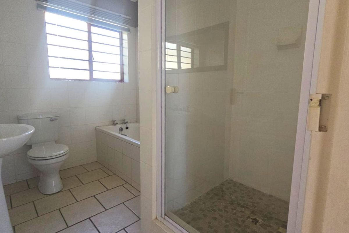 A functional bathroom featuring a pedestal basin, toilet, built-in bathtub, and a separate shower enclosure with tiled finishes throughout.