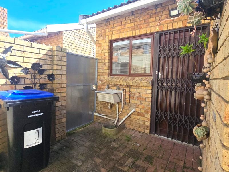 A functional rear courtyard area featuring face-brick walls, a security gate, and a built-in utility sink.