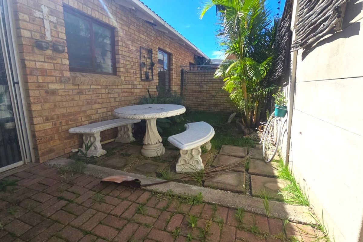A private rear courtyard featuring face brick walls, paved flooring, and direct access to the home via a sliding door.