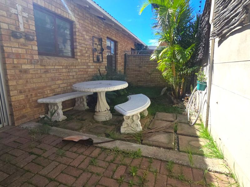 A private rear courtyard featuring face brick walls, paved flooring, and direct access to the home via a sliding door.