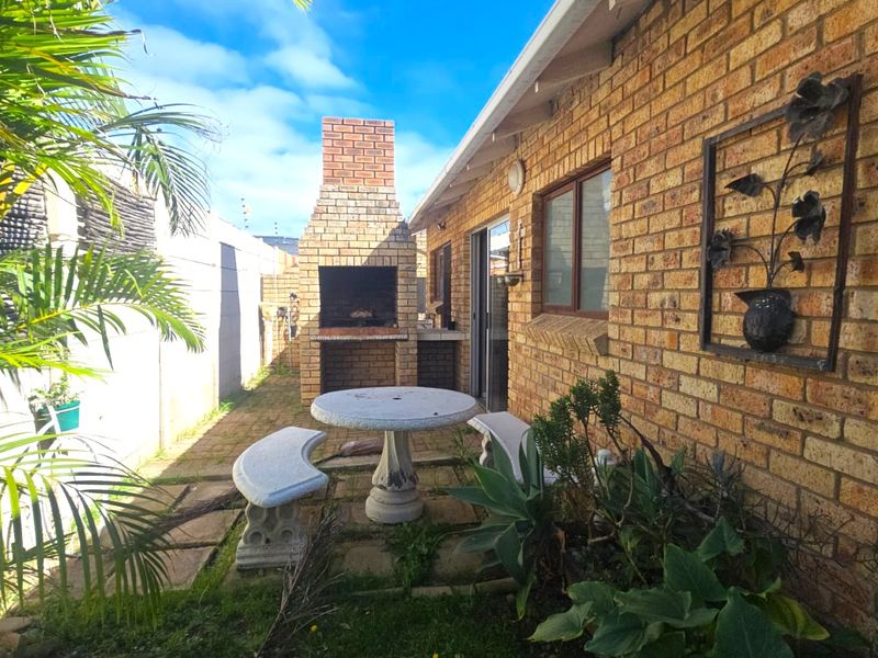 Outdoor patio area featuring a traditional brick built-in braai, paved flooring, and direct access to the home via a sliding glass door.