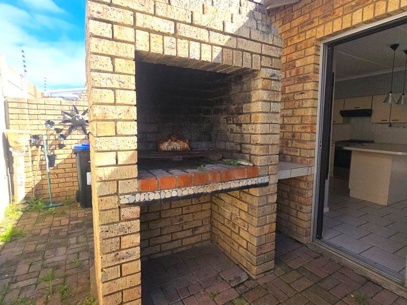 Outdoor patio area featuring a built-in brick braai and direct access to the kitchen through a sliding glass door.