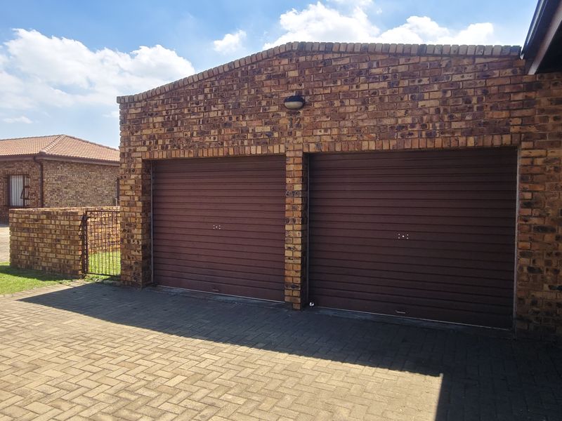 A well-maintained double garage featuring face brick construction and secure roll-up doors, situated on a paved driveway.