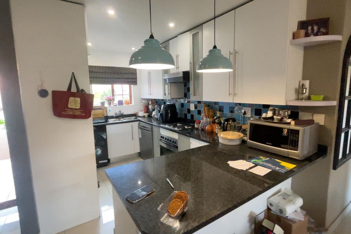 A functional kitchen featuring granite countertops, built-in cabinetry, a tiled backsplash, and integrated appliances including an oven and hob.