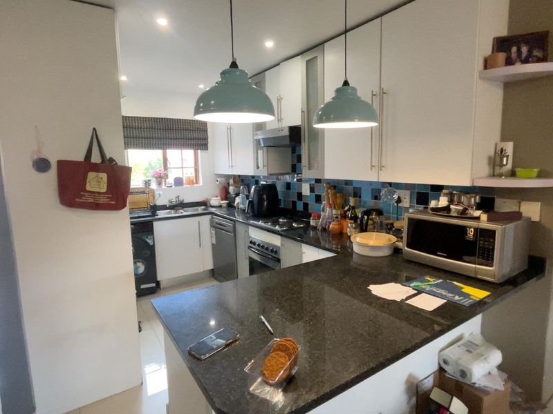 A functional kitchen featuring granite countertops, built-in cabinetry, a tiled backsplash, and integrated appliances including an oven and hob.