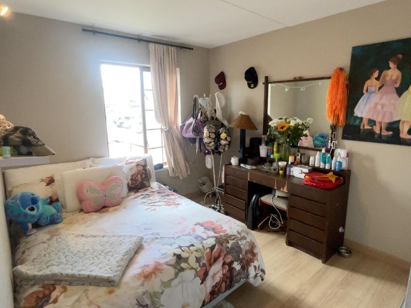 A functional bedroom featuring light-toned laminate flooring and a window with a curtain rod, providing a comfortable space for rest.