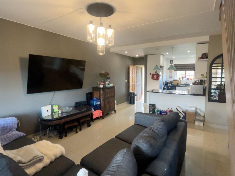 Open-plan living and kitchen area featuring tiled flooring, a breakfast bar, and modern pendant lighting, creating a functional and connected living space.