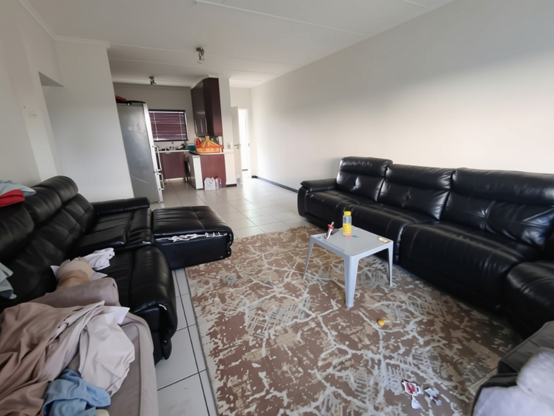 Open-plan living area featuring tiled flooring and an adjoining kitchen with built-in cabinetry, offering a functional layout for modern apartment living.