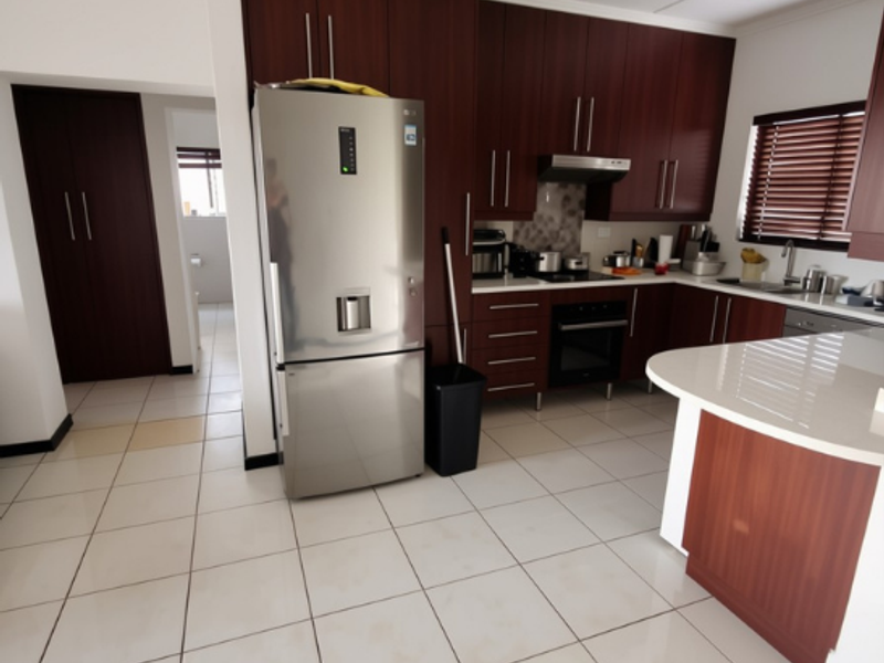 A functional kitchen featuring dark wood cabinetry, stone countertops, built-in oven, extractor fan, and tiled flooring with a breakfast bar area.
