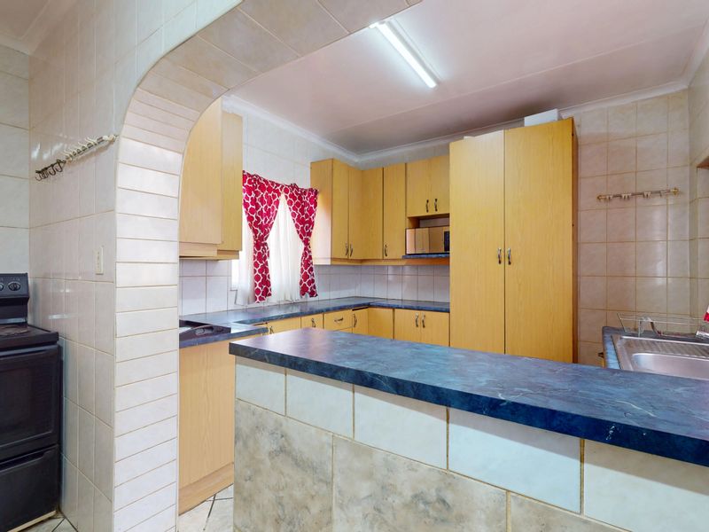 Functional kitchen featuring light wood cabinetry, blue laminate countertops, tiled backsplash, and a breakfast bar, providing a practical layout for daily meal preparation.